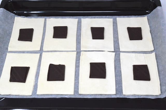 Chocolate squares on raw pastry rectangles.