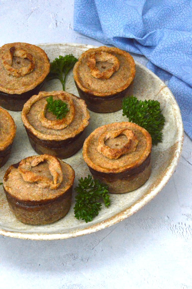 Partial view of a plate of six mini vegan mushroom pies.