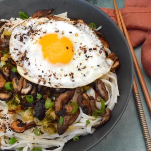A miso butter noodle bowl with cabbage, mushrooms and a fried egg.