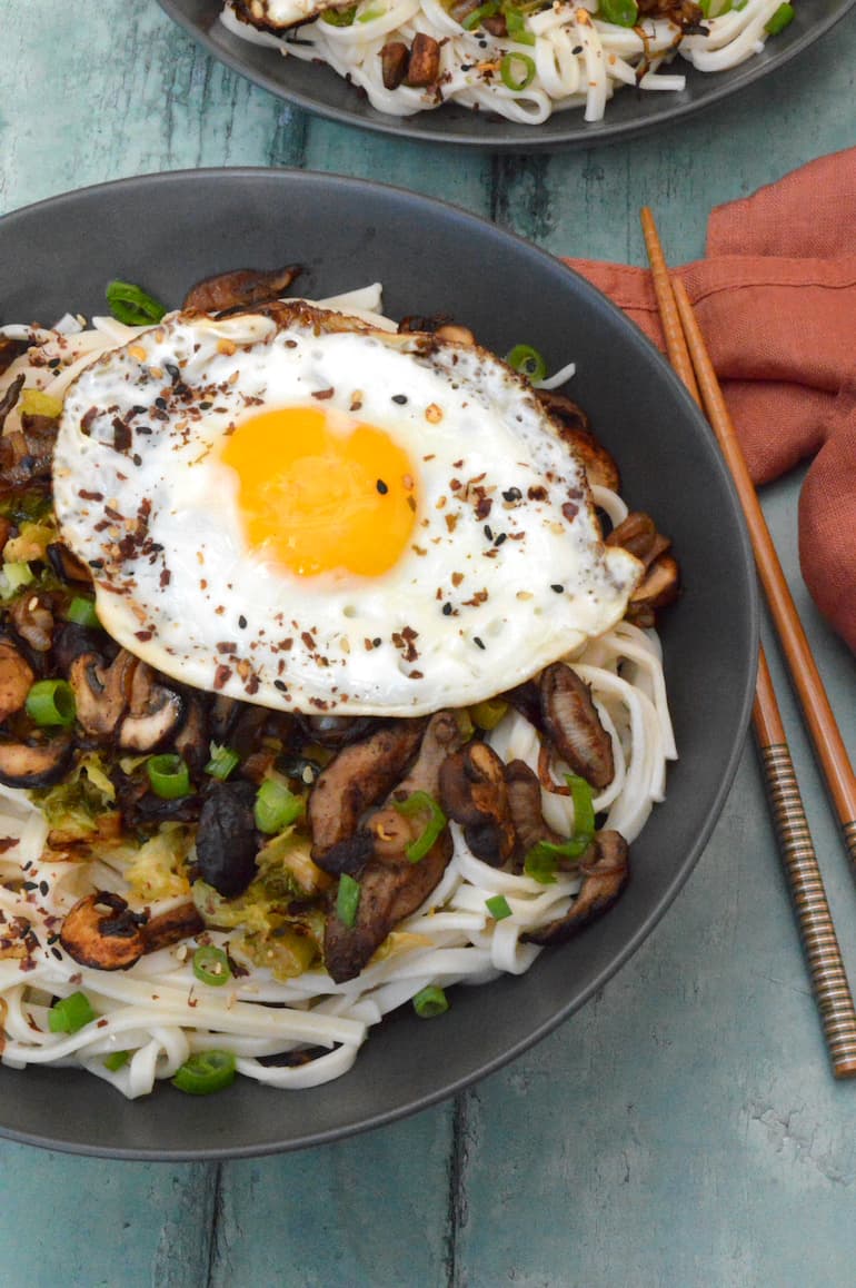 A miso butter noodle bowl with cabbage, mushrooms and a fried egg.