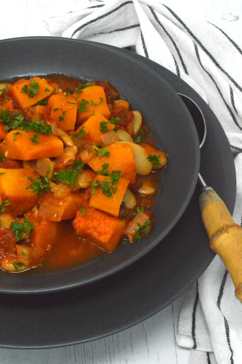 Partial view of a bowl of squash and butter bean stew.