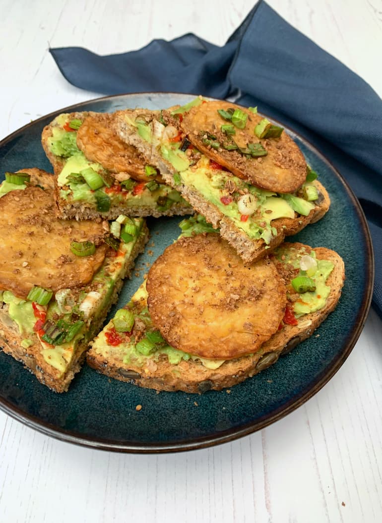 A plate of tempeh on toast with avocado, chilli, spring onions and dukkah.
