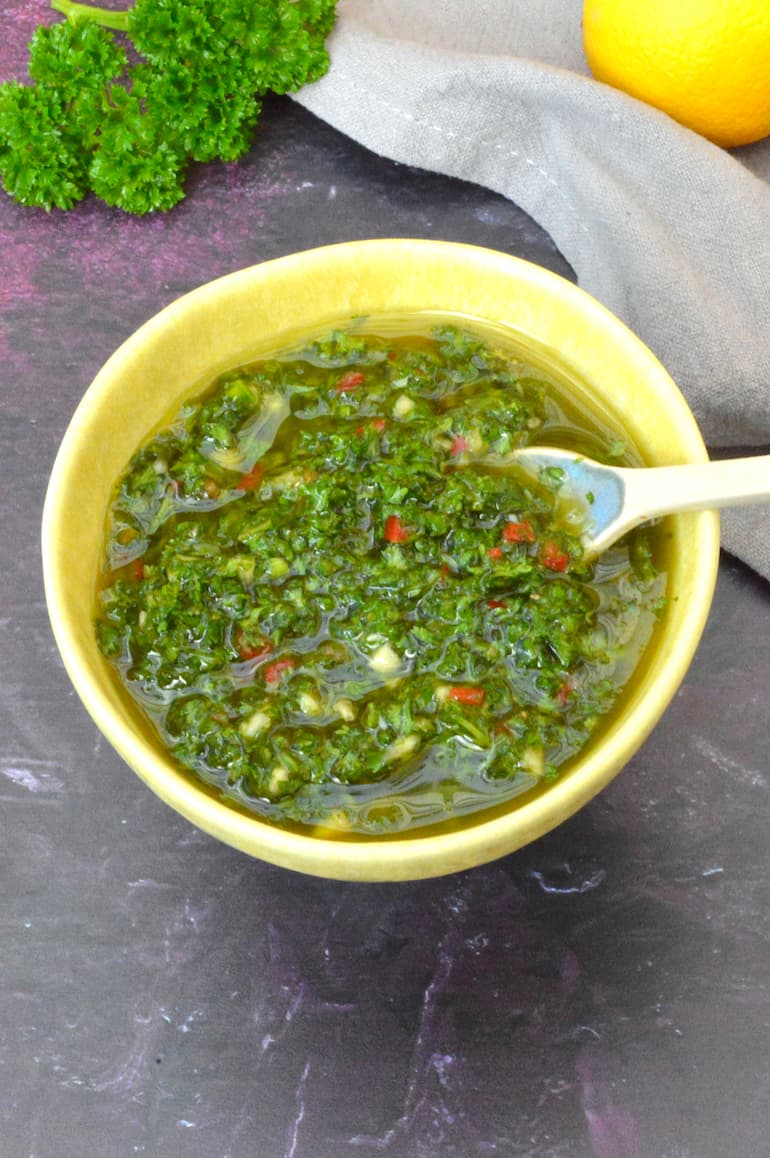 Yellow bowl filled with chimichurri sauce.