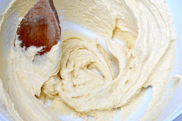 Creamed butter and sugar in mixing bowl with wooden spoon.