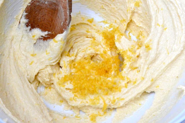 Lemon zest in bowl with creamed butter and sugar.