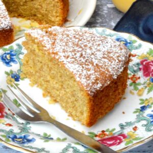 A slice of simple lemon curd cake to the fore with a jar of lemon curd behind.