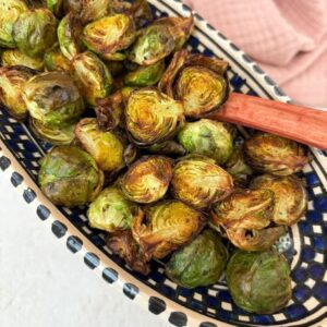 A dish of crispy air fryer Brussels sprouts with spoon.