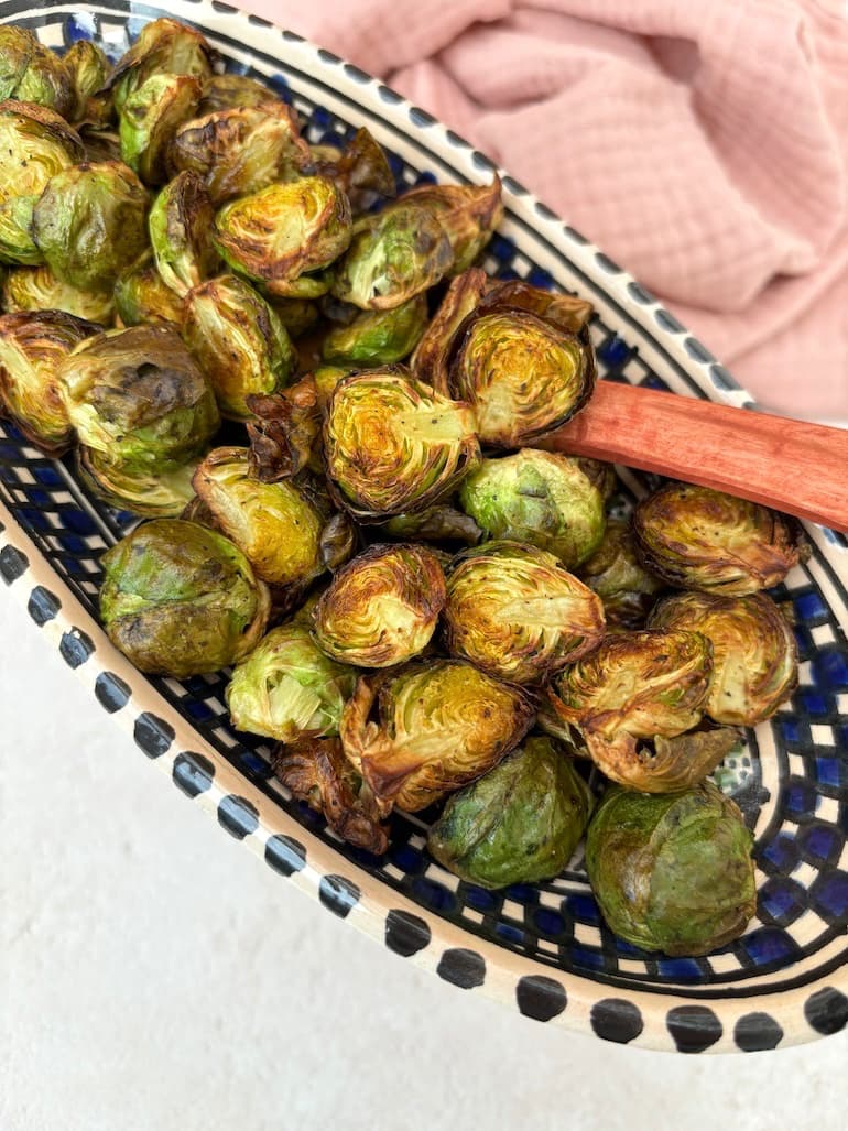 A dish of crispy air fryer Brussels sprouts with spoon.