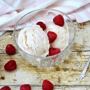 Peach Melba ice cream in bowl with raspberries.