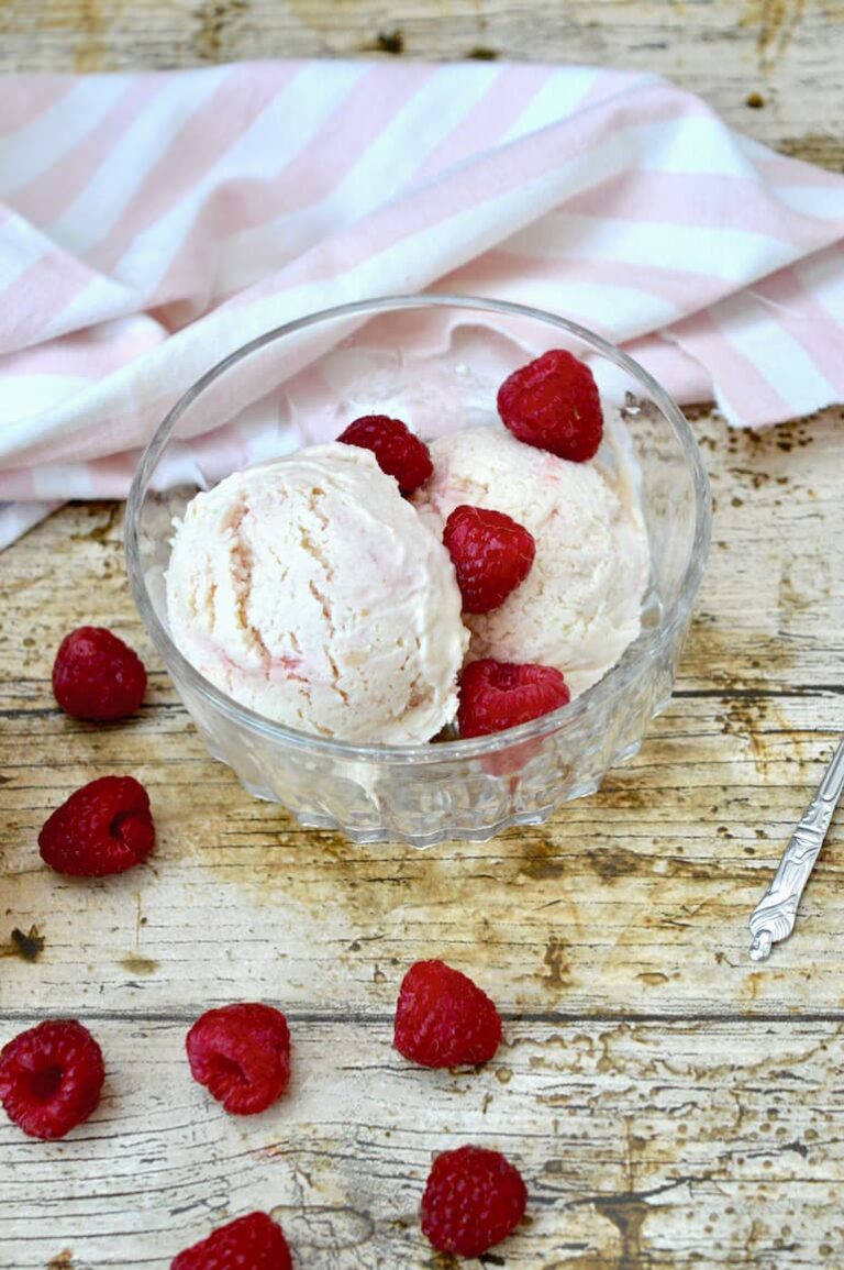 Peach Melba ice cream in bowl with raspberries.