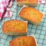 Four coconut and lime mini loaf cakes cooling on rack.