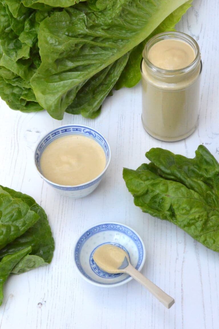 Jar, bowl and spoon of homemade caesar dressing without anchovies.