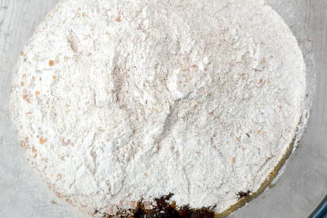 Wholemeal flour sifted over fruit in glass bowl.