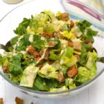 Tempeh caesar salad in bowl with dressing on side.