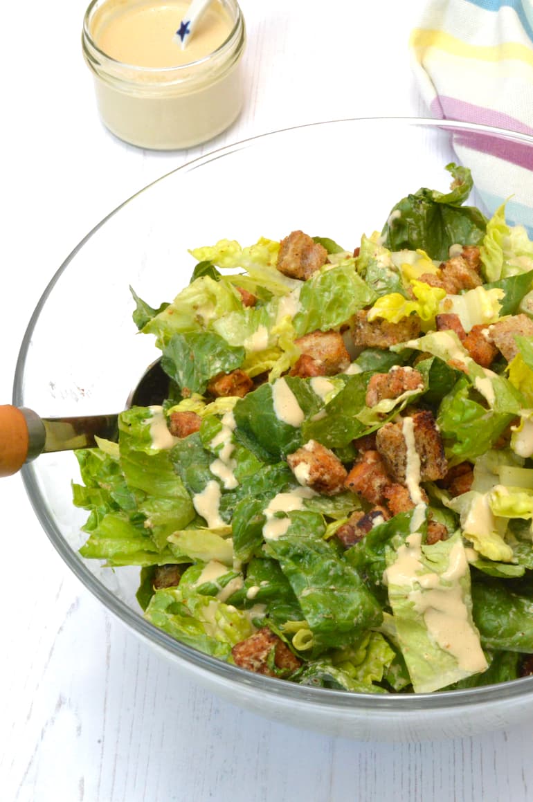 Tempeh caesar salad with jar of dressing.
