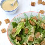 A simple vegan caesar salad with dressing on the side.