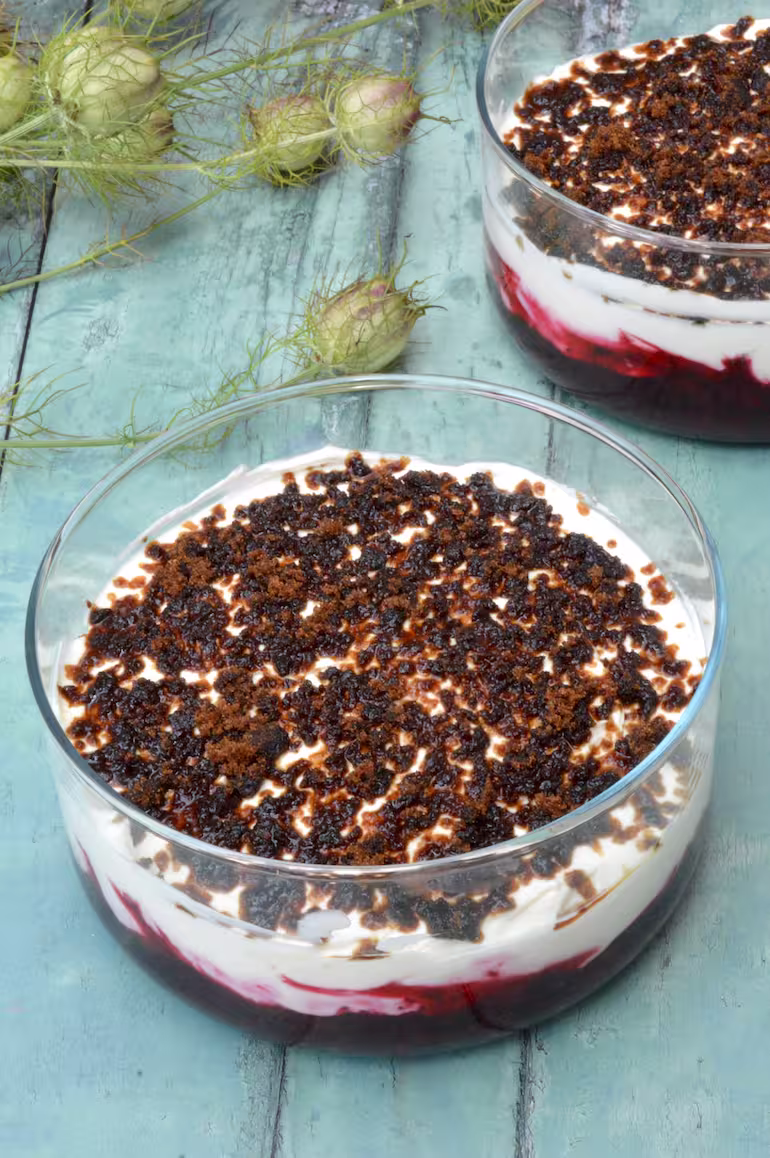 Two dishes of Norwegian cream dessert with a layer of blackcurrant compôte below.