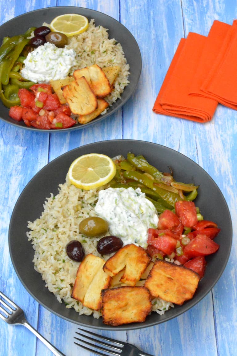 Two Greek rice nourish bowls with orange napkins.