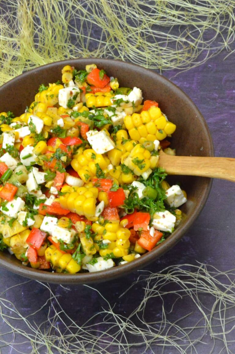 Bowl of corn salad with feta, peppers and parsley.