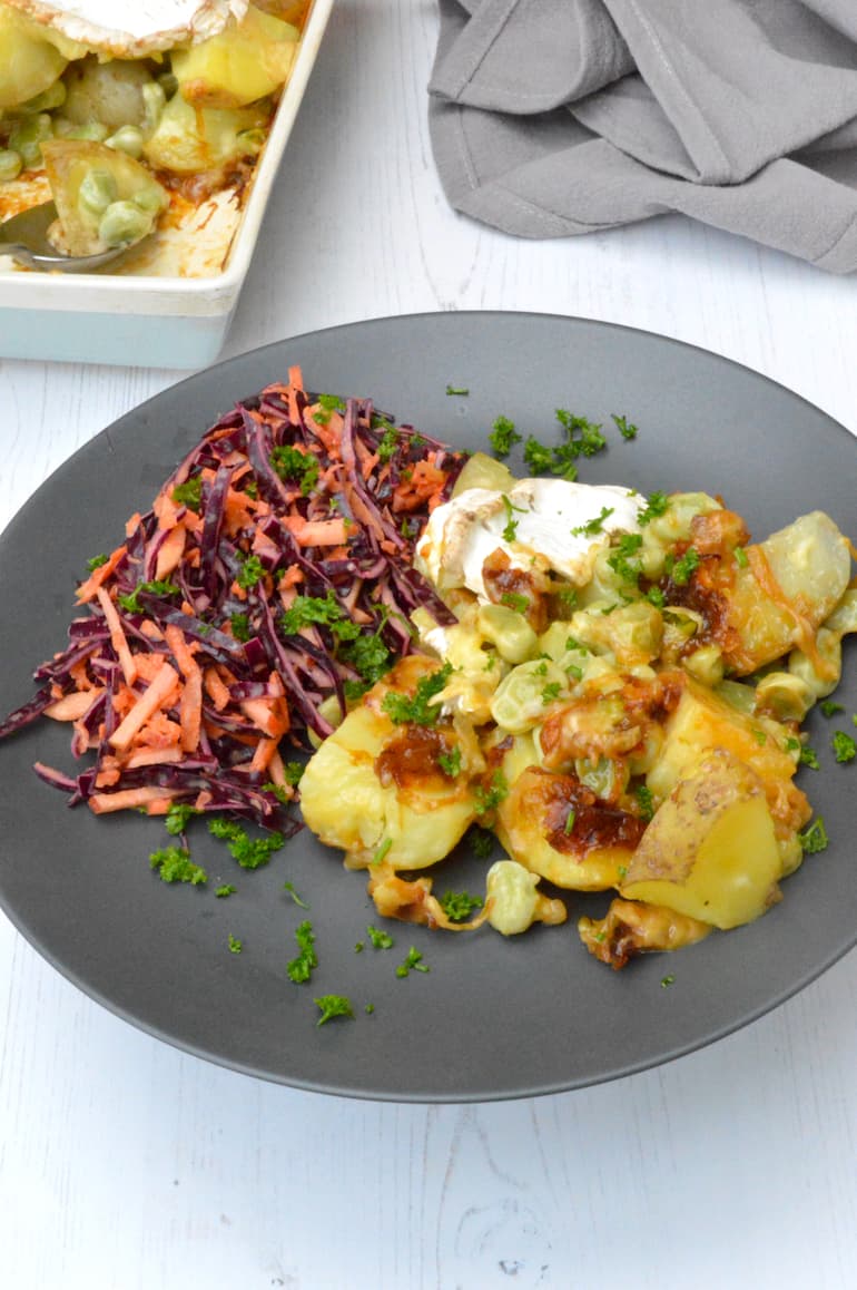 Plate of vegetarian tartiflette scattered with parsley and coleslaw on side.
