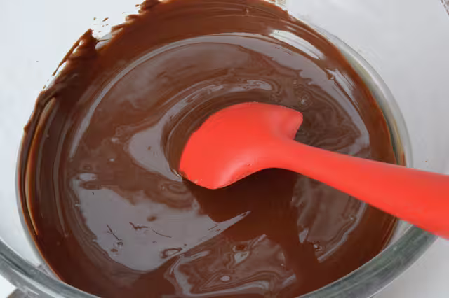 Melted chocolate in a bowl with red spatula.