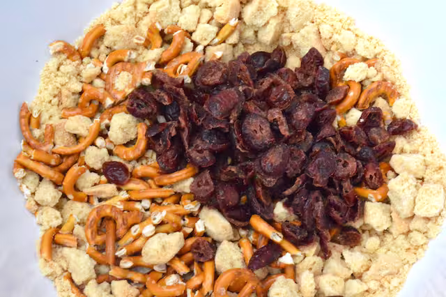 Dried cranberries in bowl with biscuit pieces.