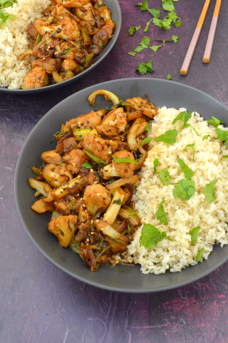 Partial view of two bowls of bang bang cauliflower with rice.