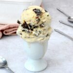 Scoops of mincemeat ice cream piled onto an eggcup with tub behind.