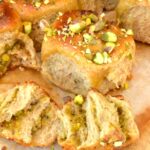 Homemade sticky orange pistachio yeasted buns with one torn open.