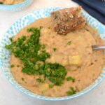 Bowl of creamy tahini white beans with bread and parsley.