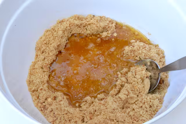 Melted butter poured into bowl of biscuit crumbs.