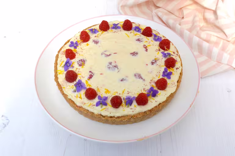 Raspberry white chocolate cheesecake decorated with raspberries and edible flowers.