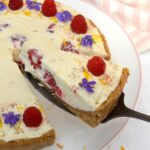 Slice of raspberry white chocolate cheesecake being served.