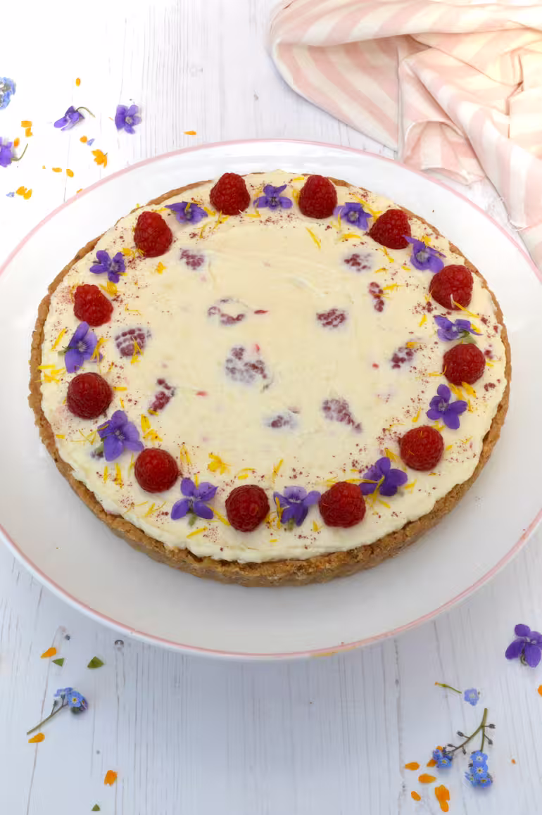 Whole raspberry white chocolate cheesecake on plate.