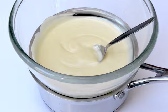 Melted white chocolate in glass bowl.