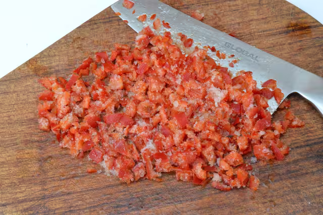 Chopped deseeded frozen rocoto chillies on board with knife.