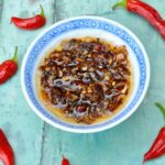 Dish of homemade crispy chilli oil with red chillies.