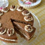 Coffee and walnut cake on stand with slice on plate alongside.