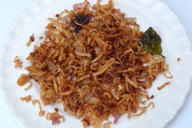 Crispy shallots spread out on plate.