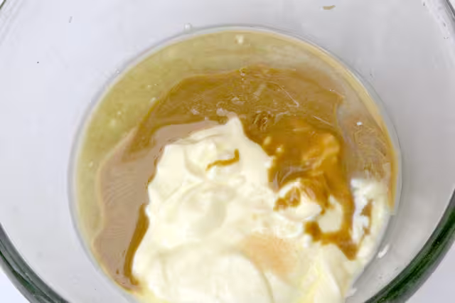 Tahini and yoghurt added to lemon juice in bowl.