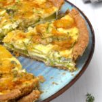 Slice of courgette and blue cheese quiche on plate with remaining tart.