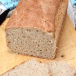 A homemade Portuguese bread loaf partially sliced.