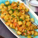 Mexican potatoes on serving dish with spoon.