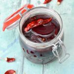 Open jar of spiced pickled beetroot slices with dried chilli.