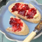 Homemade damson jam spread on a slice and a half of bread and butter.