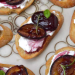 Close up of roasted plum bruschetta with whipped ricotta.