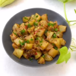 Bowl of chayote curry sprinkled with chopped parsley.