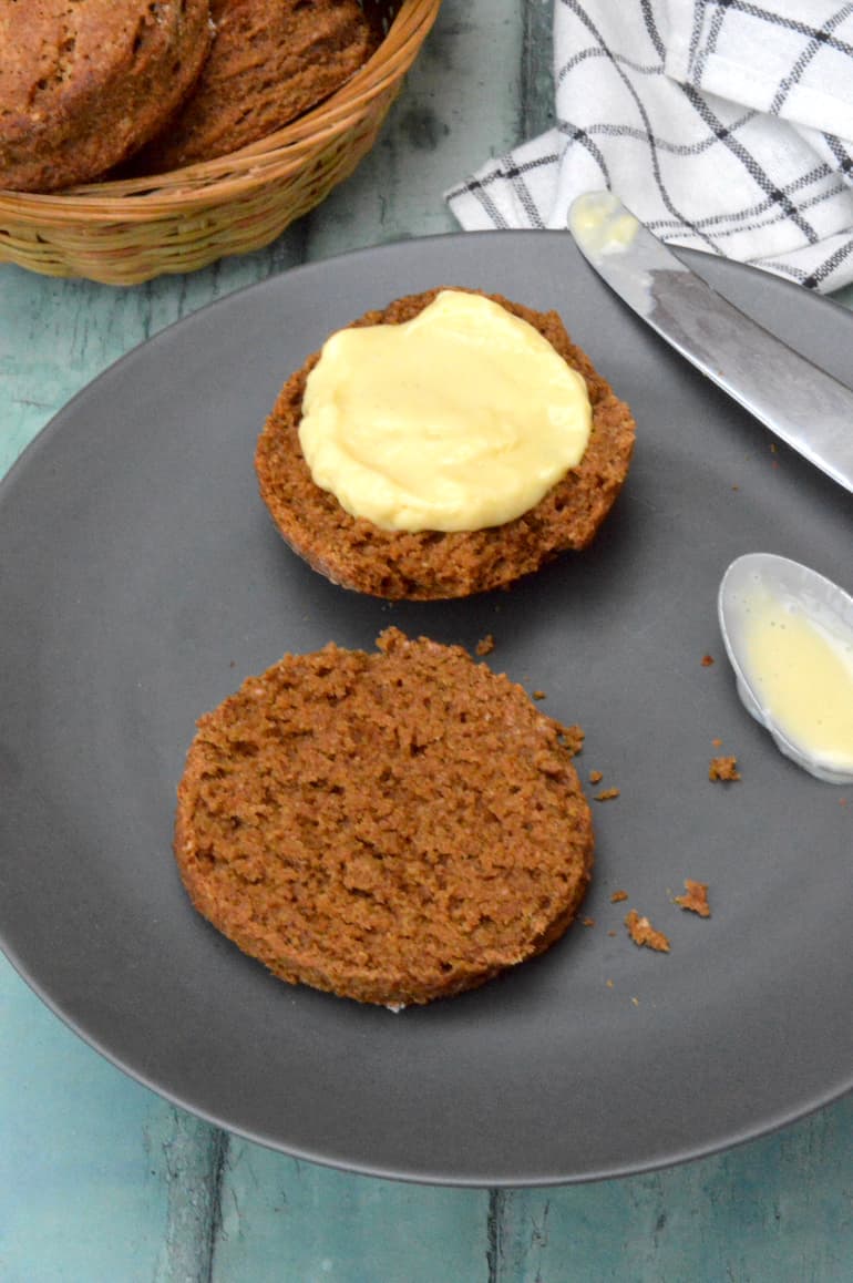 Two halves of a molasses scone on plate with one half spread with homemade lemon curd.