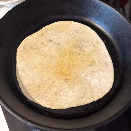 Paratha baking in cast iron skillet.