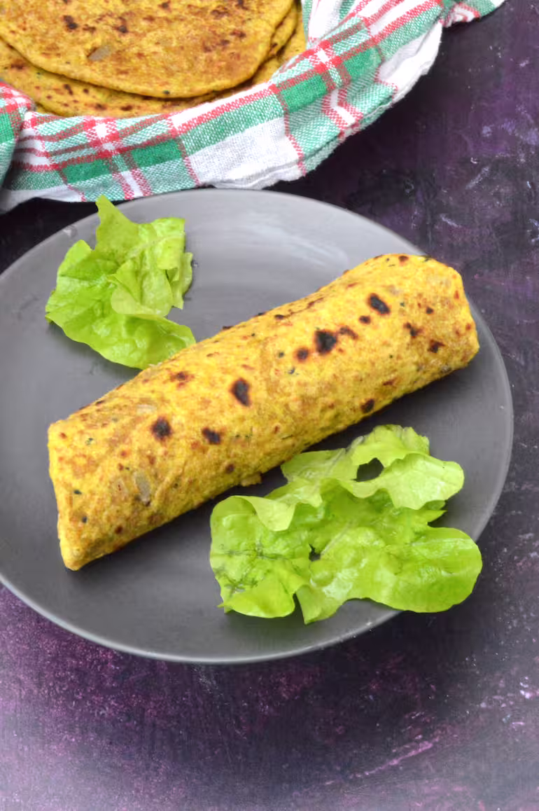 Vegan keema paratha rolled up on plate with lettuce.